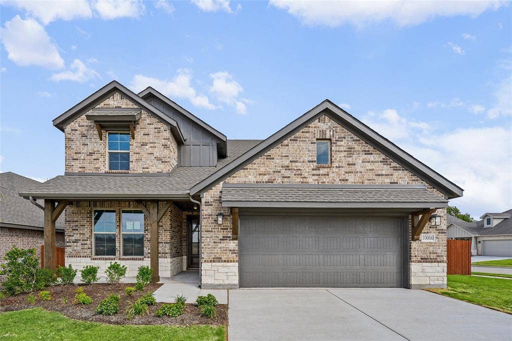 10000 Birchpoint Drive, Fort Worth, TX 76108 Brick and stone exterior with a covered entry, decorative wood columns, and an integrated two-car garage
