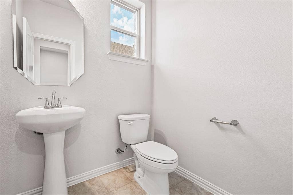 10000 Birchpoint Drive, Fort Worth, TX 76108 Pedestal sink with chrome faucet, octagonal wall mirror, and window with trim