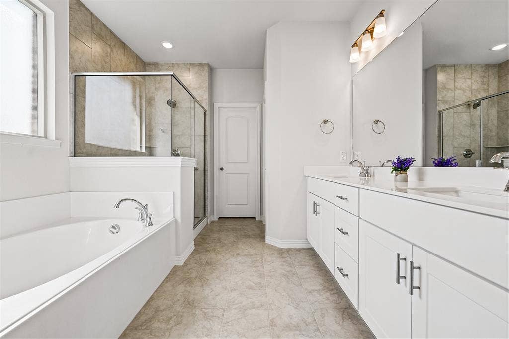 10000 Birchpoint Drive, Fort Worth, TX 76108 Dual vanity with white cabinetry, built-in bathtub, glass-enclosed shower, and tiled flooring