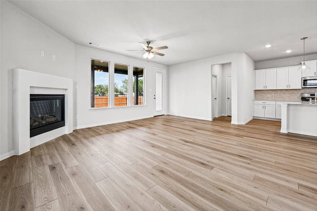 10000 Birchpoint Drive, Fort Worth, TX 76108 Wood-finish flooring throughout, multiple windows, built-in fireplace, ceiling fan, and recessed lighting