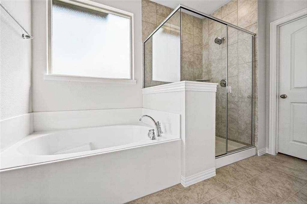 10000 Birchpoint Drive, Fort Worth, TX 76108 Built-in soaking tub with chrome fixtures, frosted glass window, separate glass-enclosed shower with tile surround, and tile flooring