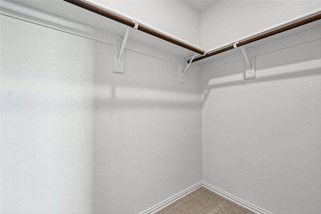 10000 Birchpoint Drive, Fort Worth, TX 76108 Corner closet with white walls, L-shaped hanging rod, and light brown carpeting