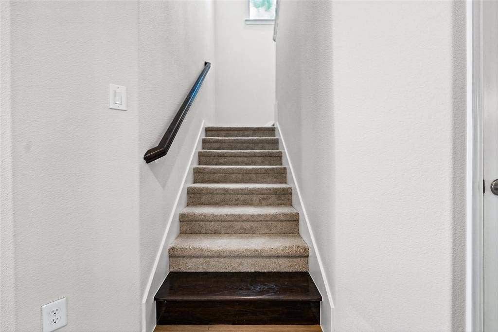 10000 Birchpoint Drive, Fort Worth, TX 76108 Staircase featuring carpeted treads, a dark wood-finish landing, and a dark handrail