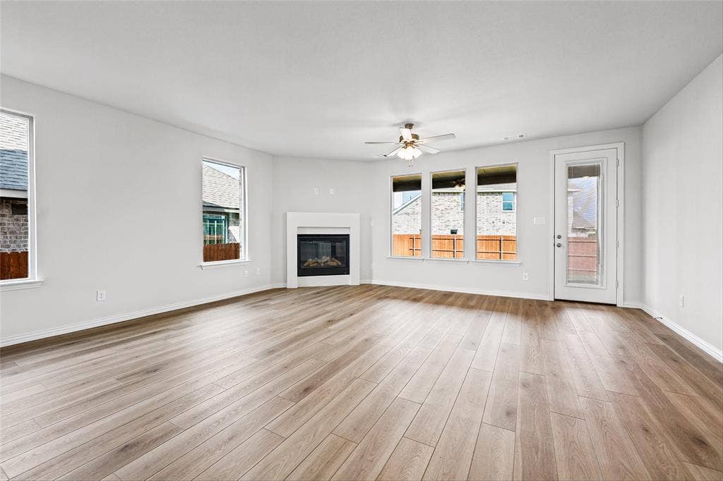 10000 Birchpoint Drive, Fort Worth, TX 76108 Expansive room featuring wood-finish flooring, multiple windows, a ceiling fan, and a built-in fireplace with a mantel