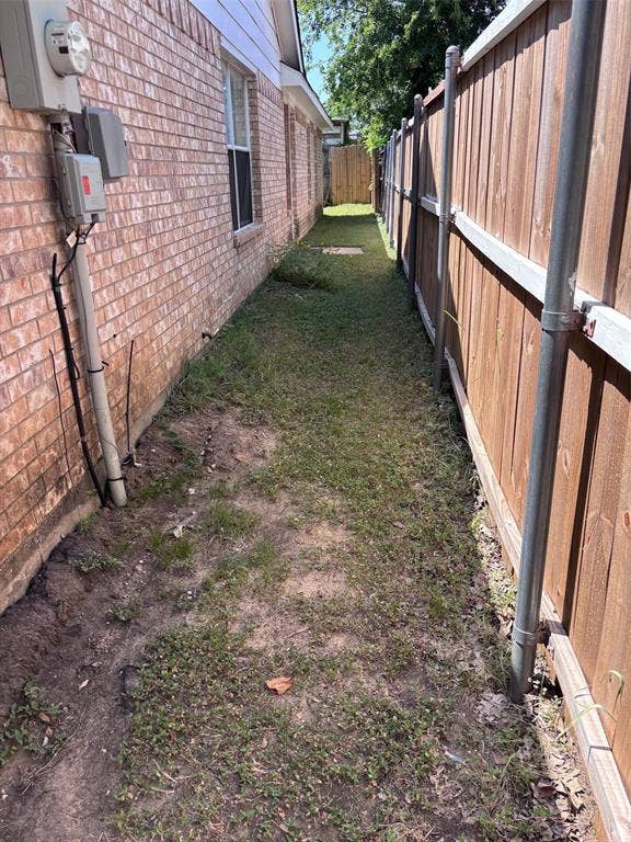 9656 Stonewood Drive, Dallas, TX 75227 Side yard featuring a red brick exterior, white trim, and a wood privacy fence