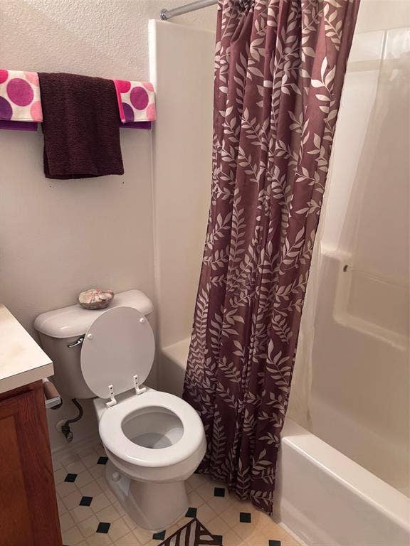 9656 Stonewood Drive, Dallas, TX 75227 Bathroom featuring a white toilet, integrated tub and shower unit, and patterned floor tiling