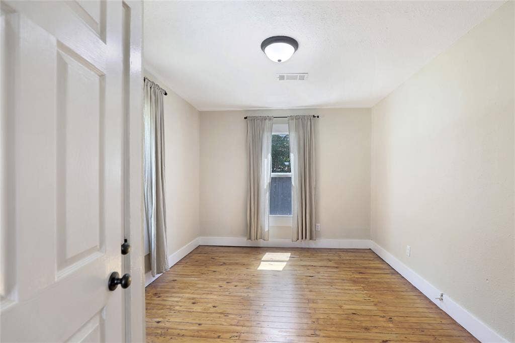1201 1/2 Cole Street, McKinney, TX 75069 Room featuring wood-finish flooring, two windows with drapery, a ceiling-mounted light fixture, and white baseboards