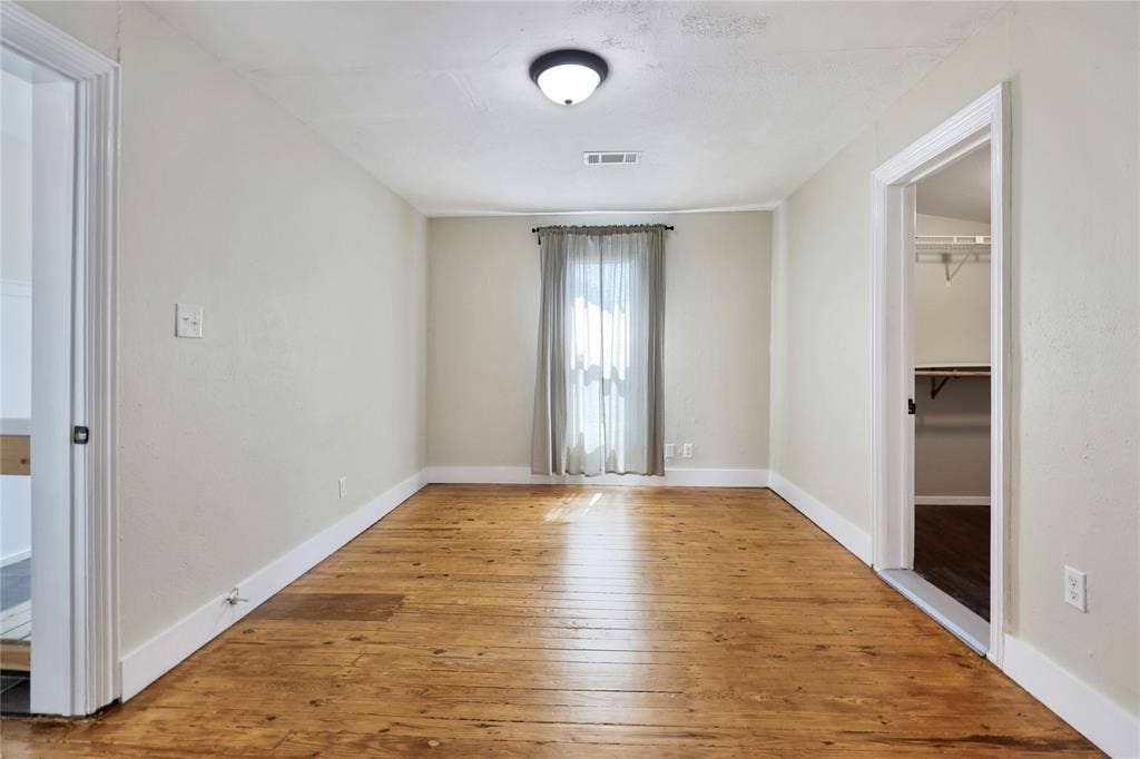 1201 1/2 Cole Street, McKinney, TX 75069 Hardwood flooring throughout this room featuring light-toned walls, a window with natural light, and a built-in closet with shelving