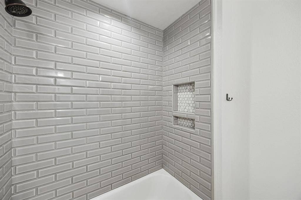 3624 Churchill Lane, Plano, TX 75075 Gray subway tile laid in a classic brick pattern gives the renovated guest shower a clean and timeless finish.