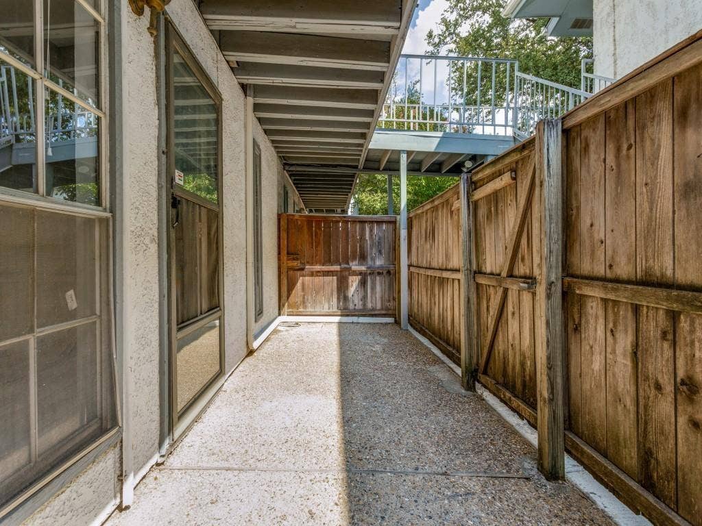 12888 Montfort Drive, #155, Dallas, TX 75230 Private outdoor corridor featuring a concrete walkway, wood privacy fencing, and multiple windows