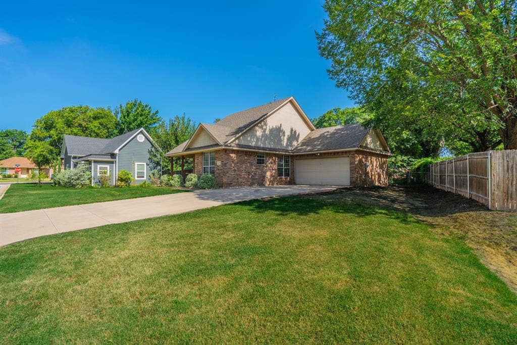 403 Summer Tree Lane, Springtown, TX 76082 Brick exterior with an attached garage, landscaping, and a fenced yard