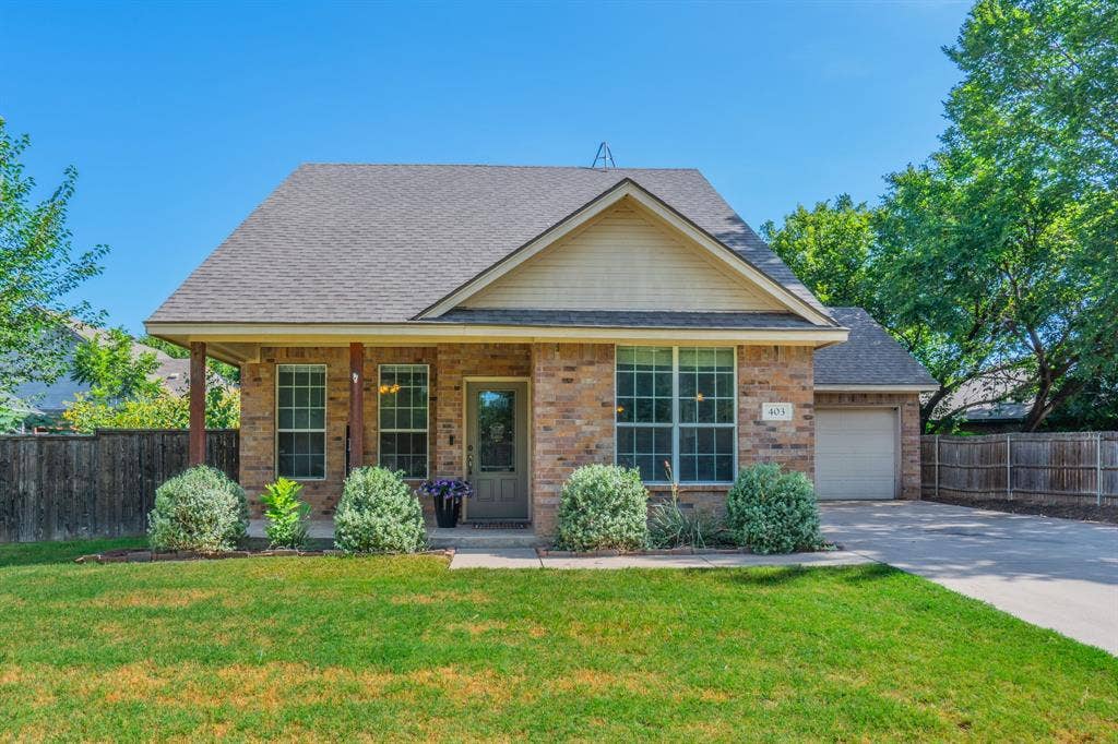 403 Summer Tree Lane, Springtown, TX 76082 Front of brick home featuring covered porch and 2-car garage.