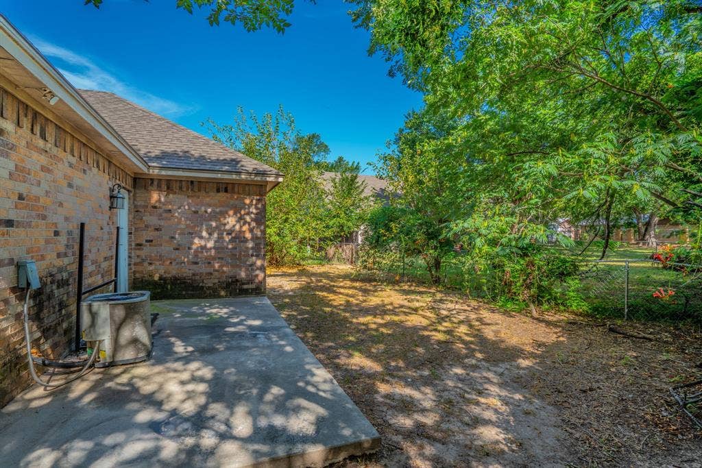 403 Summer Tree Lane, Springtown, TX 76082 Rear of property featuring a concrete patio slab and a fenced yard.
