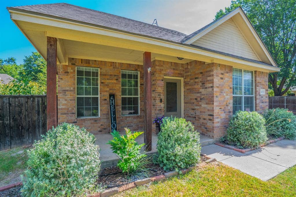 403 Summer Tree Lane, Springtown, TX 76082 Brick home featuring a covered front porch and established shrubbery