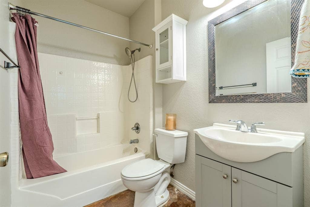 403 Summer Tree Lane, Springtown, TX 76082 Primary bathroom featuring a white tub/shower combination, a vanity with an integrated sink, a large framed mirror, and a wall-mounted storage cabinet