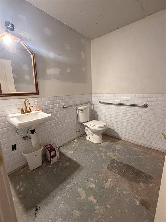 122 W Mccart Street, Krum, TX 76249 Pedestal sink with brass-finish faucet, toilet, and subway tile wainscoting