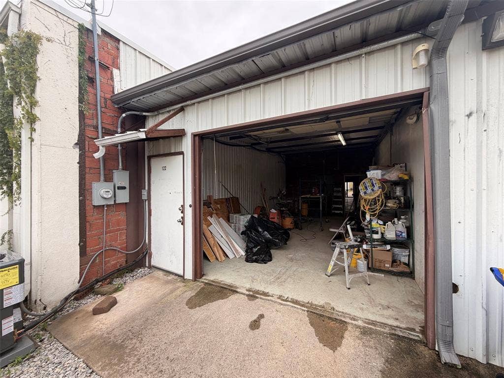 122 W Mccart Street, Krum, TX 76249 Metal-clad structure featuring a roll-up door and a pedestrian entry door