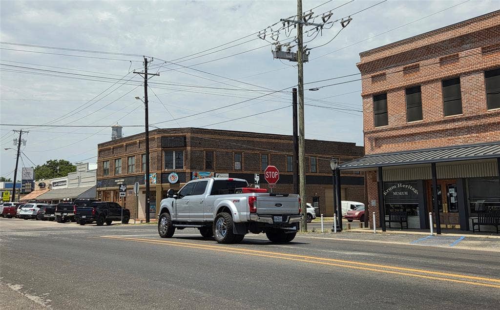 122 W Mccart Street, Krum, TX 76249 Historic commercial buildings featuring brick facades and ground-level retail spaces in downtown area. Showcasing one of the main intersections nearby.