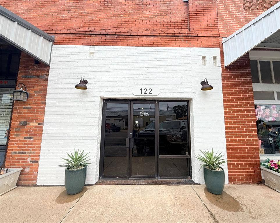 122 W Mccart Street, Krum, TX 76249 Brick facade with a white painted lower section and dual entry doors