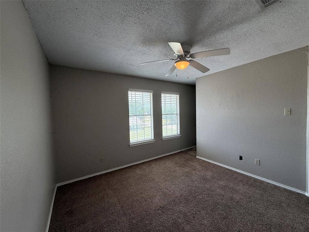 Unfurnished room featuring ceiling fan, carpet flooring, and a textured ceiling