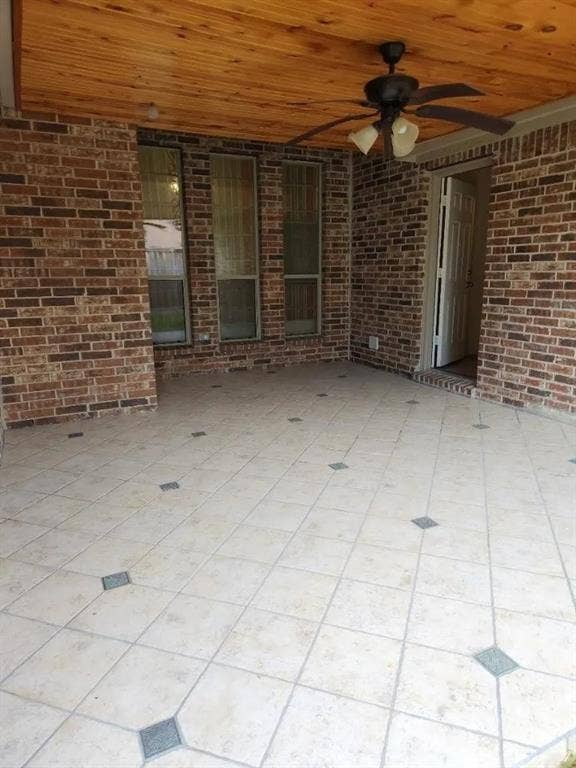 1214 Alabama Court, Murphy, TX 75094 Covered patio featuring a wood-finish ceiling, ceiling fan with integrated lighting, brick exterior walls, and tiled flooring with decorative inlays