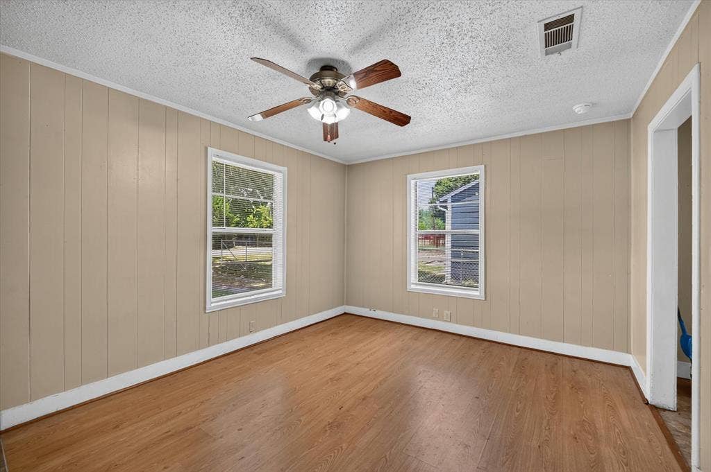 4450 Percy Street, Lancaster, TX 75134 Room featuring wood-finish flooring, two large windows, a ceiling fan with integrated lighting, and board-and-batten wall paneling