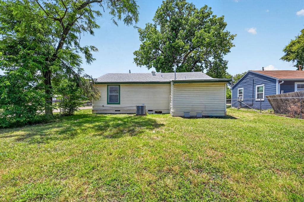 4450 Percy Street, Lancaster, TX 75134 Rear exterior featuring cream siding, green trim, a single window, and a visible HVAC unit