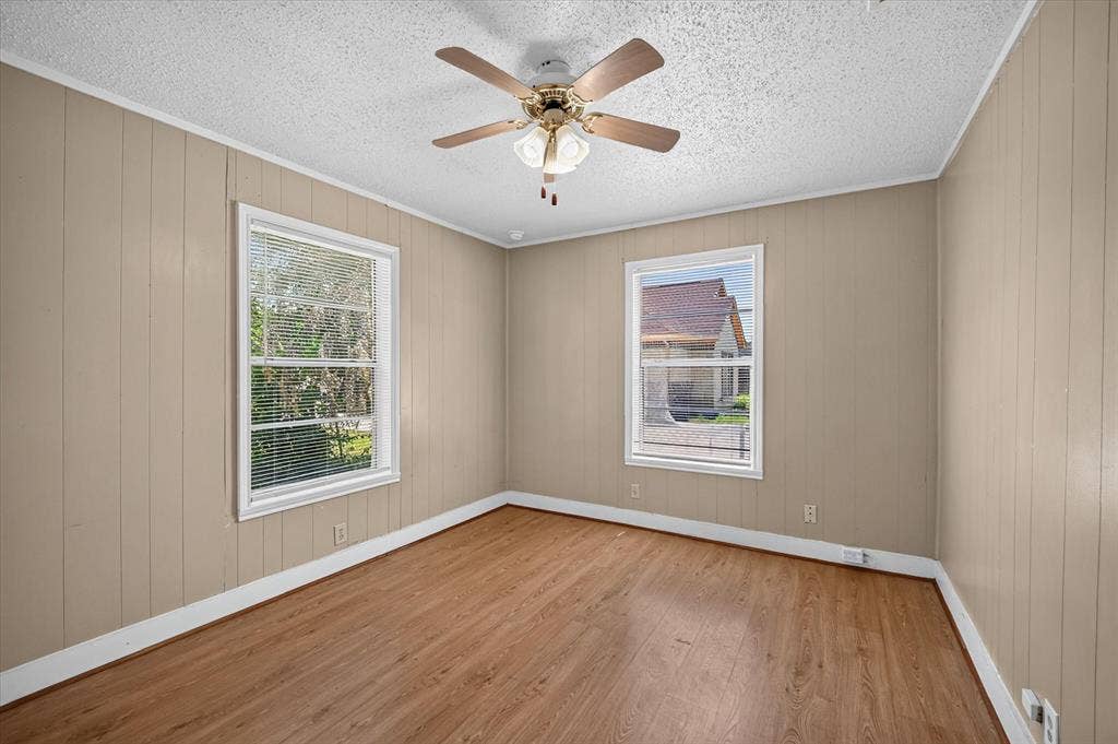 4450 Percy Street, Lancaster, TX 75134 Room featuring wood-finish flooring, two windows with blinds, a ceiling fan with integrated lighting, and paneling walls