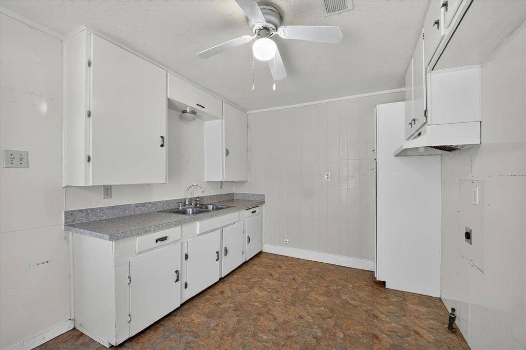 4450 Percy Street, Lancaster, TX 75134 Kitchen featuring white cabinetry, a dual basin stainless steel sink, a gray speckled countertop, and resilient flooring