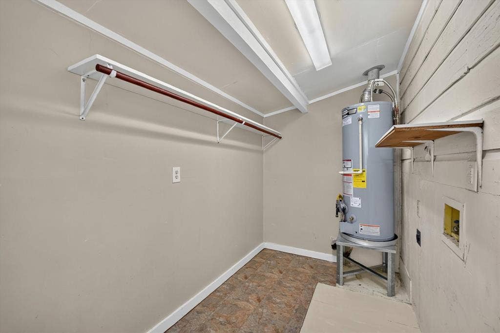 4450 Percy Street, Lancaster, TX 75134 Laundry area featuring water heater, wall-mounted shelving, and clothes hanging rod