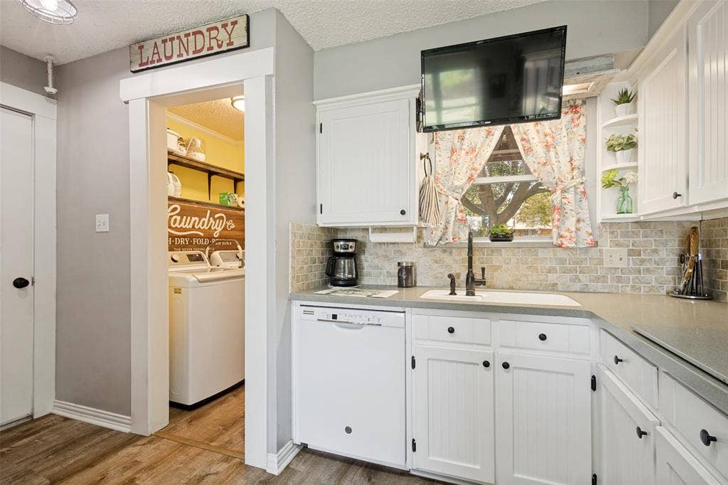 906 Clearview Street, Krum, TX 76249 Kitchen area featuring white cabinetry with black hardware, a light-toned countertop, and a tiled backsplash