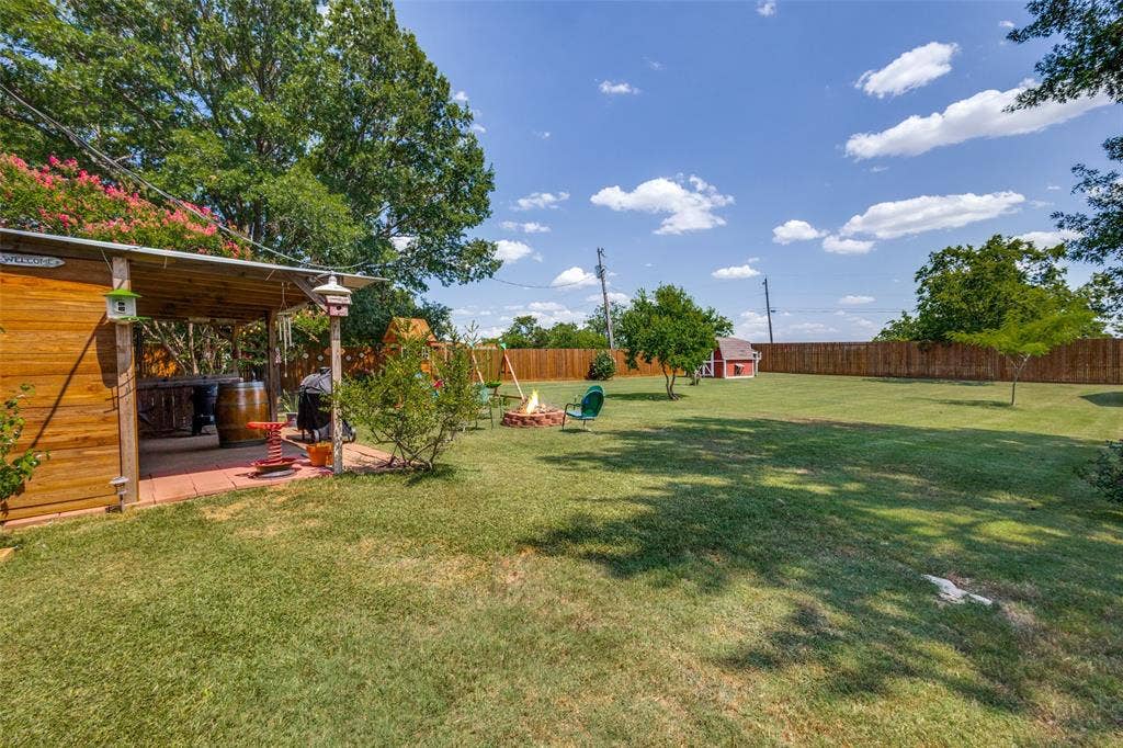 906 Clearview Street, Krum, TX 76249 Expansive backyard featuring a covered patio with mature trees, and a privacy fence