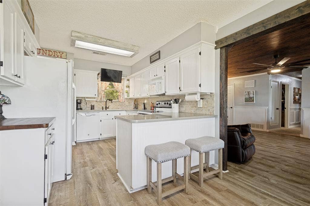 906 Clearview Street, Krum, TX 76249 Kitchen featuring white cabinetry, LVP flooring, a tile backsplash, and an integrated ceiling light fixture