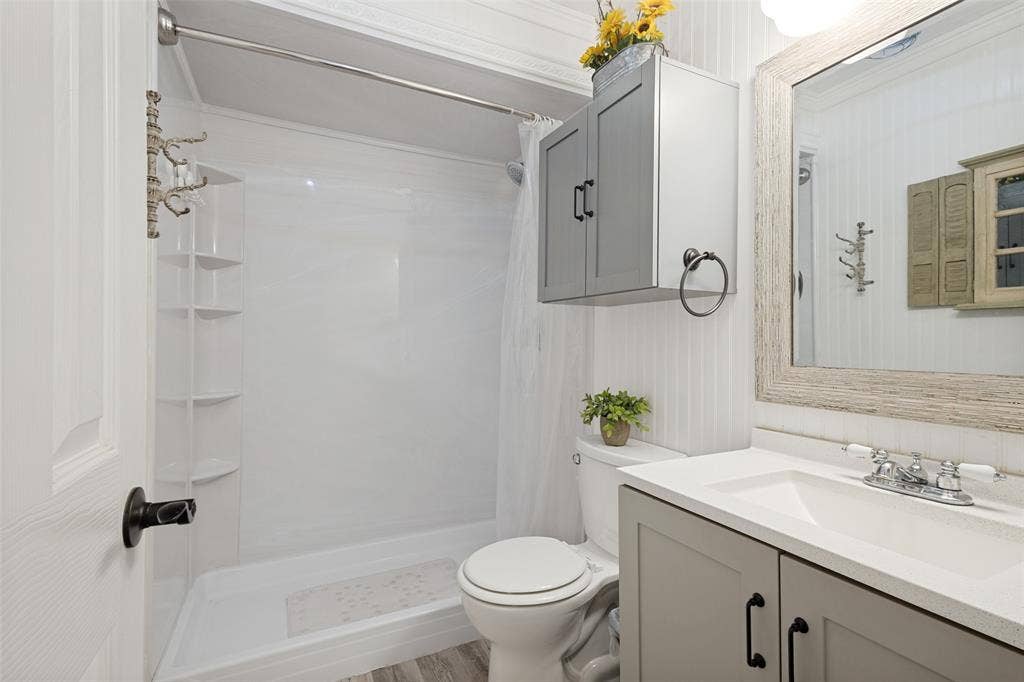 906 Clearview Street, Krum, TX 76249 Bathroom featuring a single vanity with a white countertop and undermount sink, a framed mirror, and a walk-in shower.