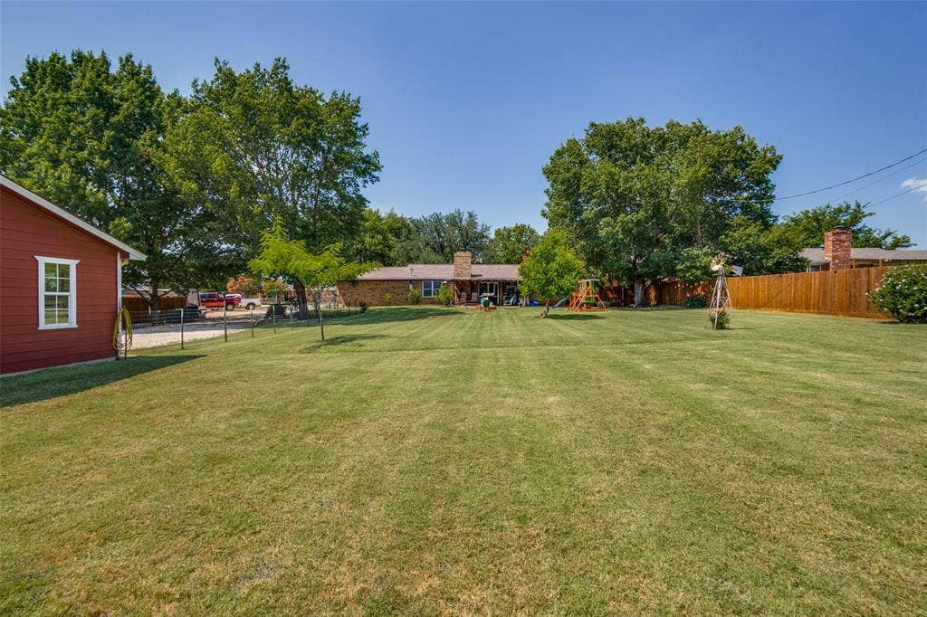 906 Clearview Street, Krum, TX 76249 Expansive green lawn with mature trees and a red-sided outbuilding