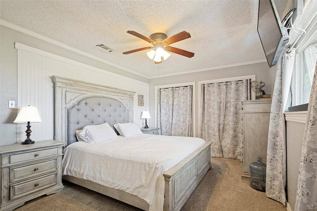 906 Clearview Street, Krum, TX 76249 Primary bedroom featuring light gray walls, textured carpet flooring, and a ceiling fan.