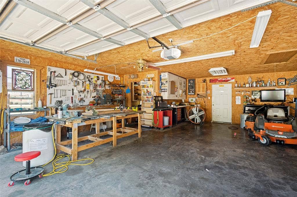 906 Clearview Street, Krum, TX 76249 Spacious garage featuring a finished interior with wood-paneled walls and a concrete floor