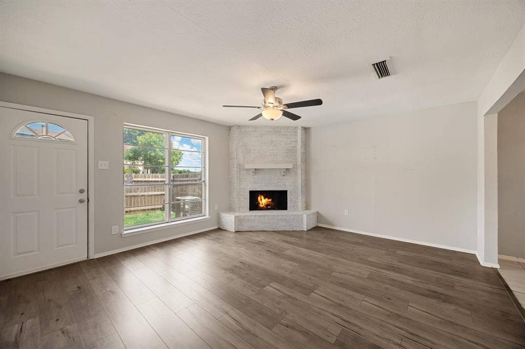 1 E Mountain Lane, #33, Grand Prairie, TX 75052 Spacious living area featuring wood-finish flooring, a white brick fireplace with a mantle, and large windows