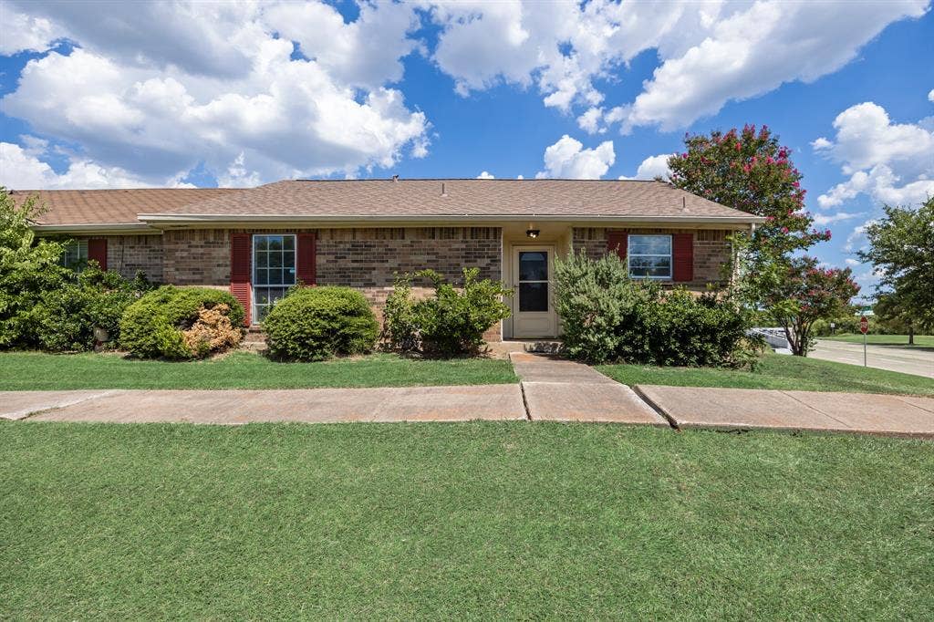 1 E Mountain Lane, #33, Grand Prairie, TX 75052 Brick exterior with red shutters, a prominent front door, and a well-maintained sidewalk