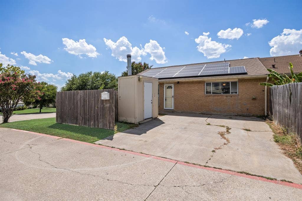 1 E Mountain Lane, #33, Grand Prairie, TX 75052 Rear exterior featuring brick siding, solar panels, and a concrete patio