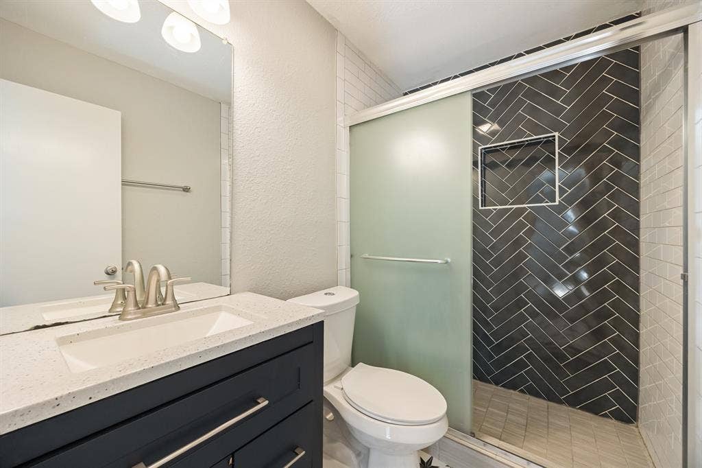 1 E Mountain Lane, #33, Grand Prairie, TX 75052 Bathroom featuring a vanity with an integrated sink, a quartz-finish countertop, and a dark wood-finish cabinet