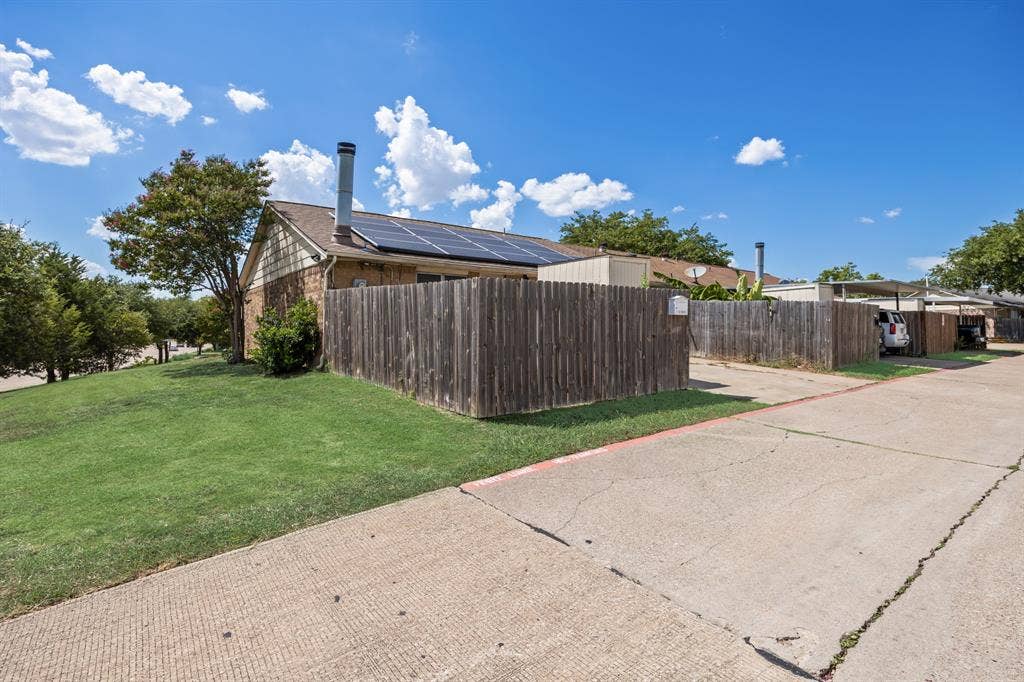 1 E Mountain Lane, #33, Grand Prairie, TX 75052 Exterior featuring a brick facade, shingle roof, solar panels, and a wood privacy fence