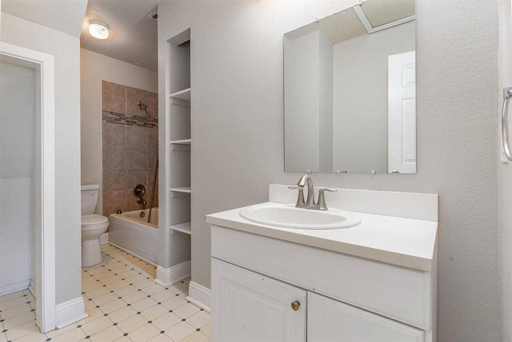 500 S Ballard Avenue, Wylie, TX 75098 Bathroom featuring a single-sink vanity with white countertop, chrome faucet, and mirrored medicine cabinet