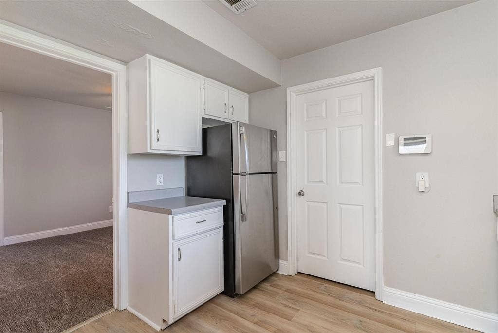 500 S Ballard Avenue, Wylie, TX 75098 Compact kitchen area featuring white cabinetry, a light-toned countertop, and stainless steel refrigerator