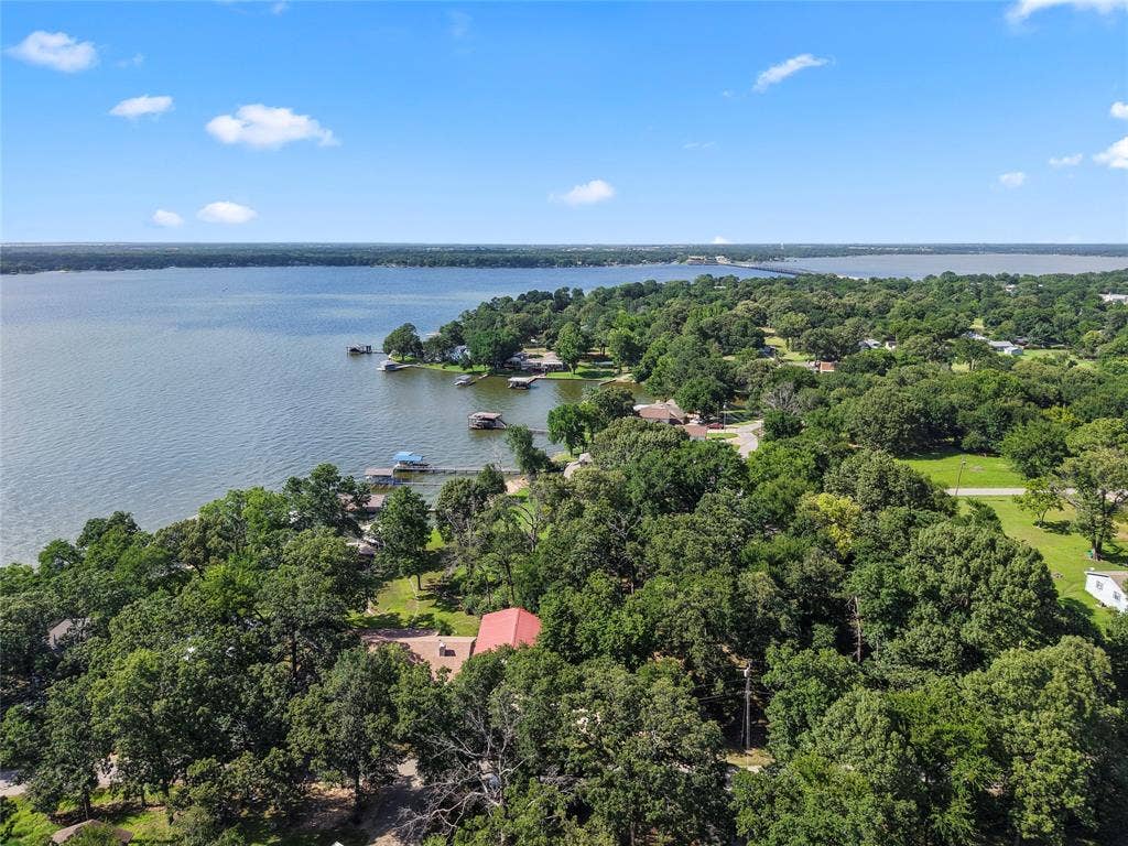 323 Dyer Circle, Payne Springs, TX 75156 Expansive waterfront property featuring a red-roofed residence amidst mature trees