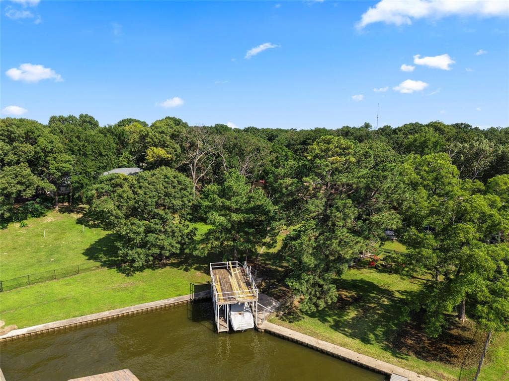 323 Dyer Circle, Payne Springs, TX 75156 Waterfront property featuring a private boat dock, concrete retaining wall, and expansive green lawn