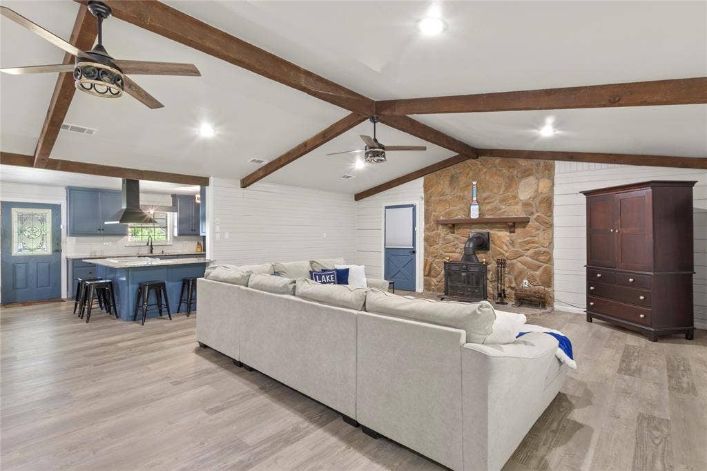 323 Dyer Circle, Payne Springs, TX 75156 Spacious open-concept living area featuring a stone fireplace, exposed wood beams, and wood-finish flooring