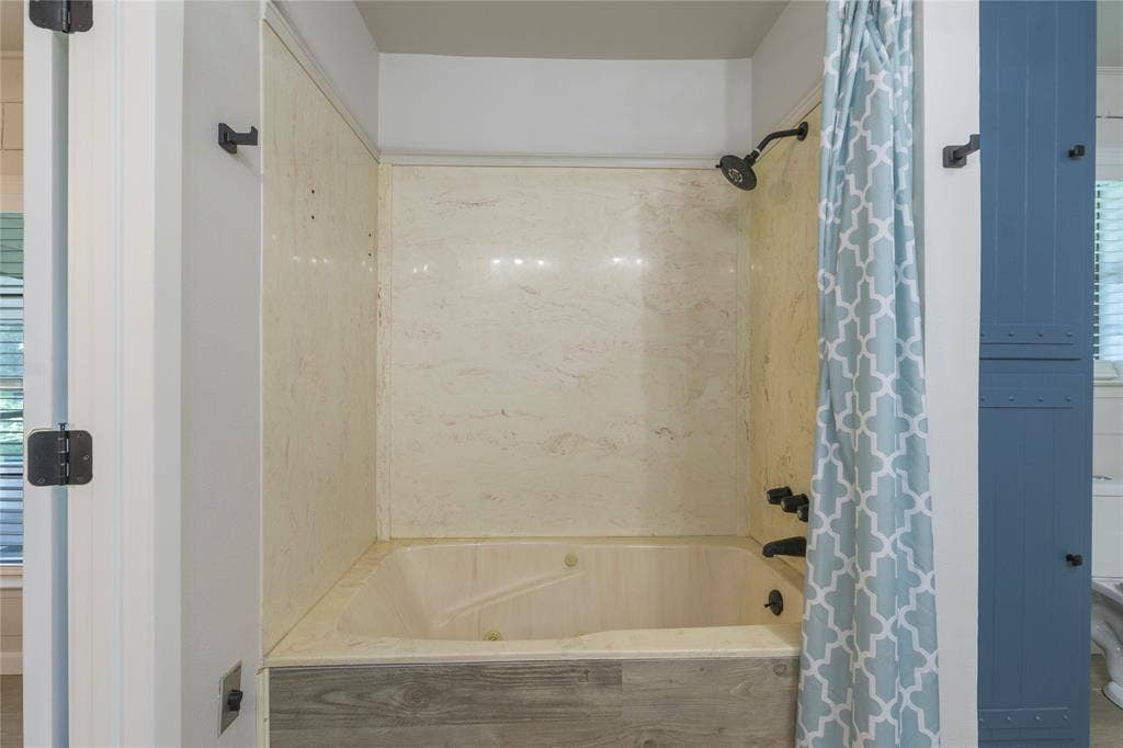 323 Dyer Circle, Payne Springs, TX 75156 Tub/shower combination featuring a light-toned surround and dark-finish fixtures, complemented by a wood-finish tub skirt