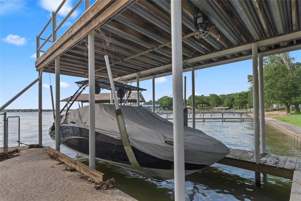 323 Dyer Circle, Payne Springs, TX 75156 Covered boat dock featuring a boat lift, corrugated metal roof, and a wood decking upper level