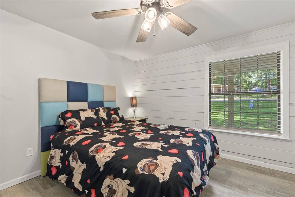 323 Dyer Circle, Payne Springs, TX 75156 Bedroom featuring a shiplap accent wall, wood-finish flooring, and a ceiling fan with integrated lighting